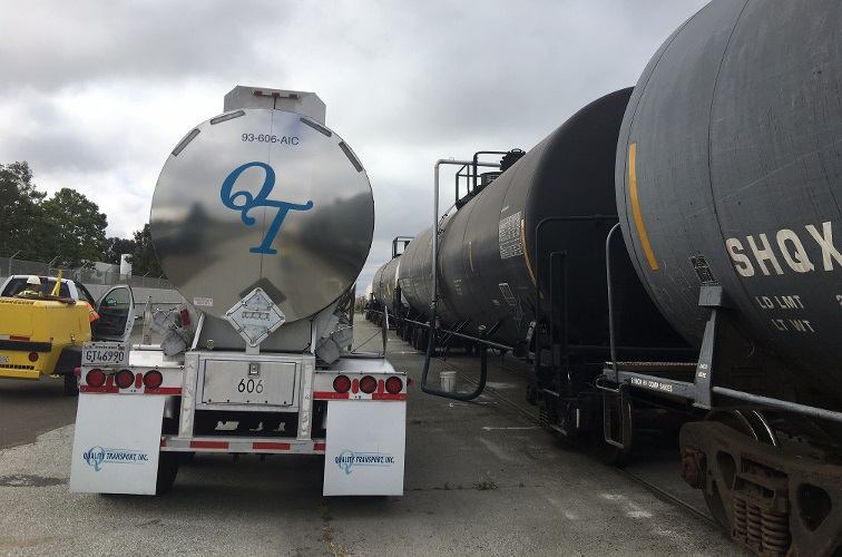 Using a candy cane device, Truck-Rail Handling transloads recycled oil from a truck to a tank car.